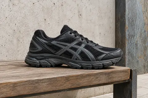 Sneaker Asics Gel-Mission noire et anthracite posée sur un banc en bois, semelle visible dans un décor urbain sobre.