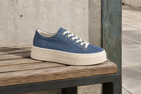 Baskets à plateforme en toile bleu denim posées sur un banc en bois dans un décor urbain sobre.