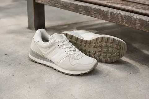 Baskets rétro-running New Balance 515 Sea Salt posées près d’un banc en bois dans un décor urbain