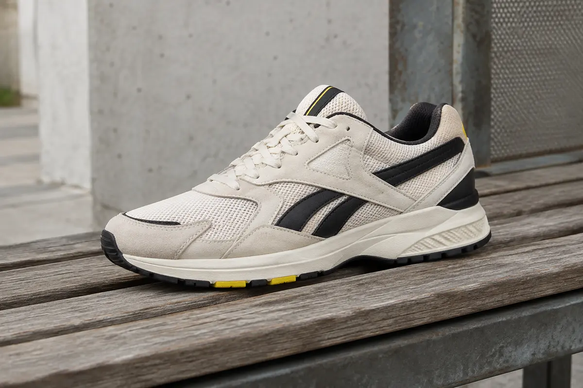 Sneaker Reebok Glide en mesh posée sur un banc de bois dans un décor urbain sobre.